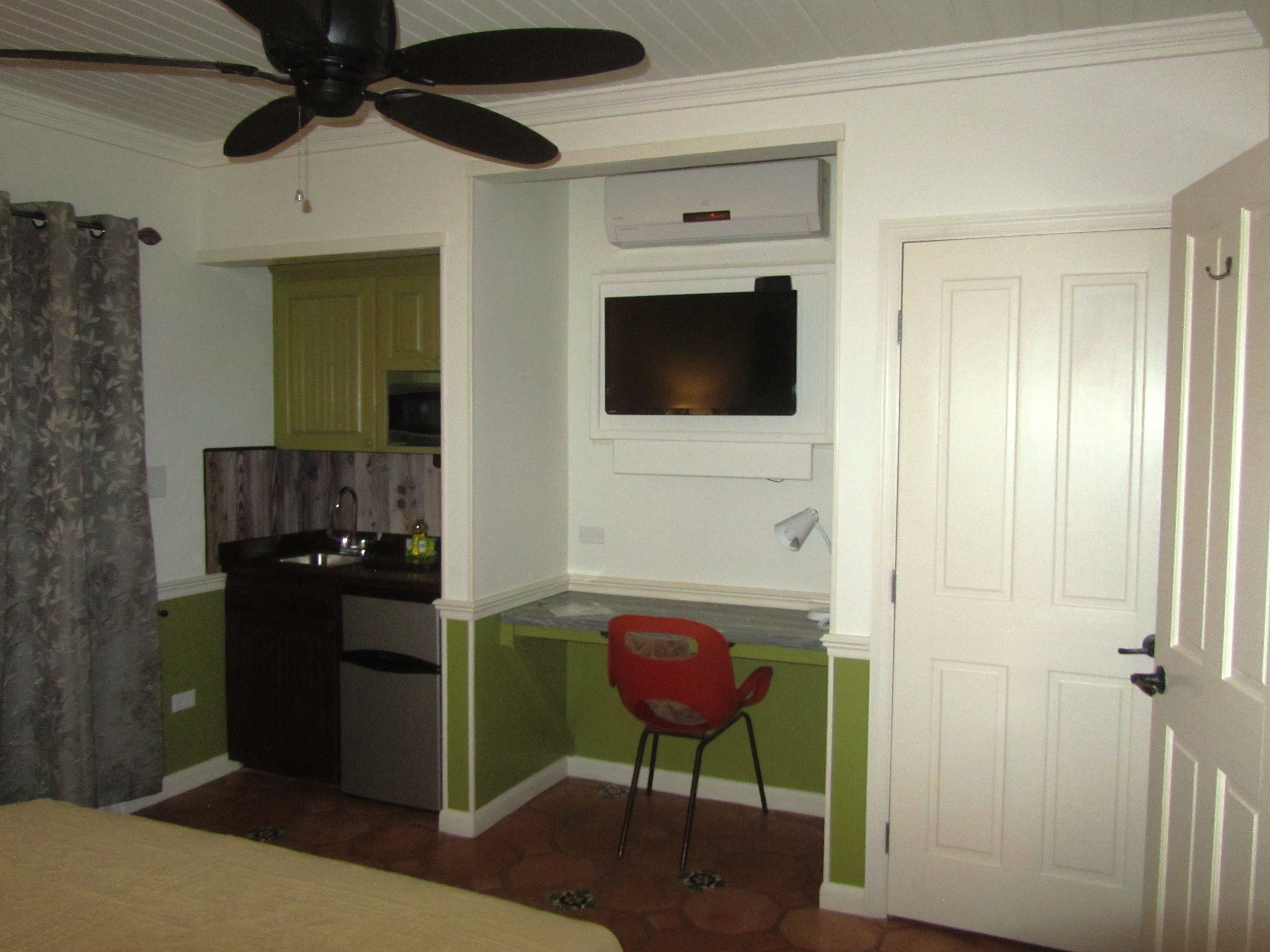 A compact kitchen with a ceiling fan, a microwave, and a small refrigerator.