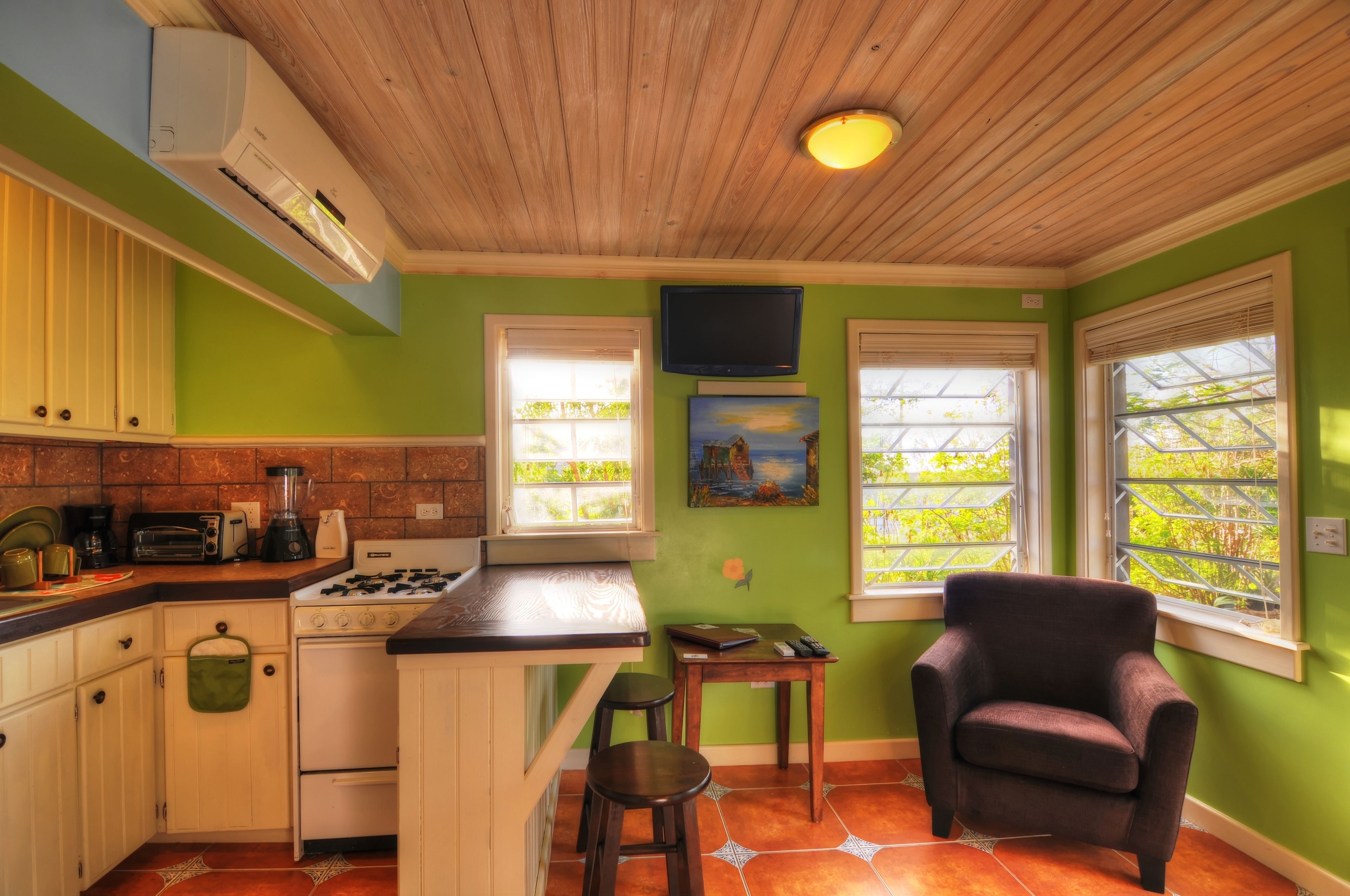 A kitchen with a gas stove, a sink, and a window with a view of greenery.