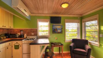 A kitchen with a gas stove, a sink, and a window with a view of greenery.
