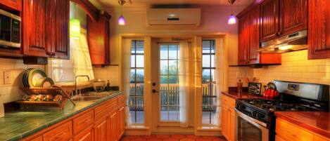 Une cuisine avec des meubles de rangement en bois, une cuisinière et une fenêtre donnant sur un balcon.