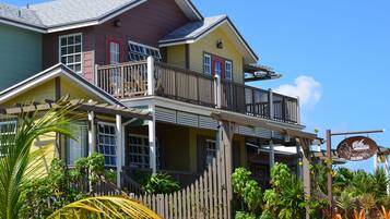 A multi-story building with a balcony, a signboard, and lush tropical plants.