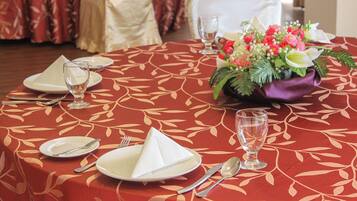 Mesa posta para quatro pessoas, com toalha vermelha, guardanapos brancos e um arranjo floral.