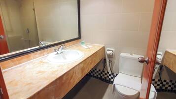 Un baño con lavamanos de mármol, inodoro y ducha.