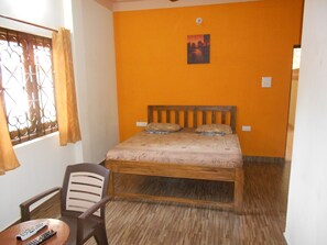 Una habitación con una cama, una silla y una mesa con dos mandos a distancia.