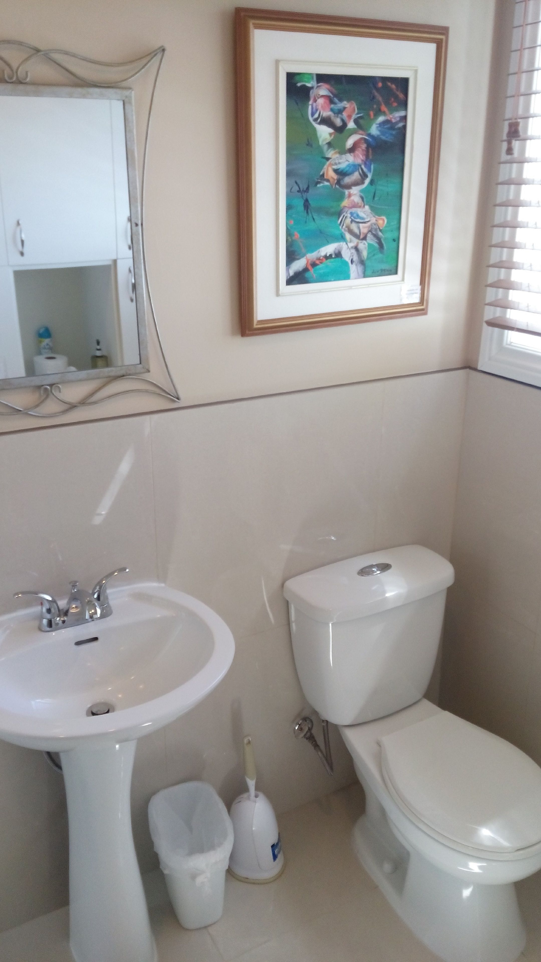 Een badkamer met een wit wastafel, toilet en een wandeling met een lijst.