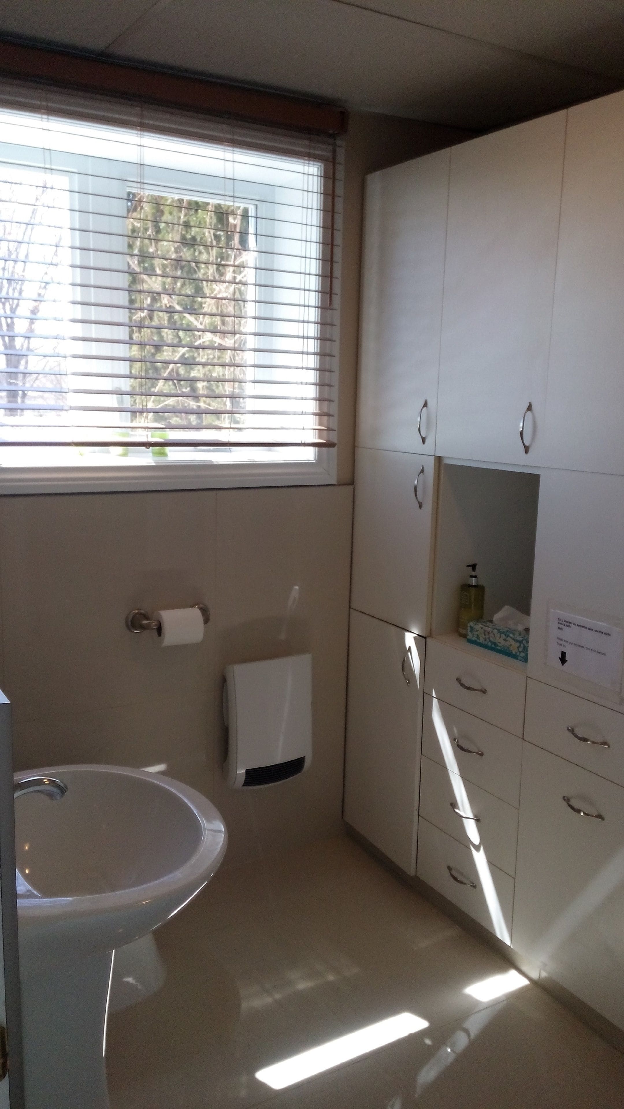 A bathroom with a sink, toilet, and cabinets.