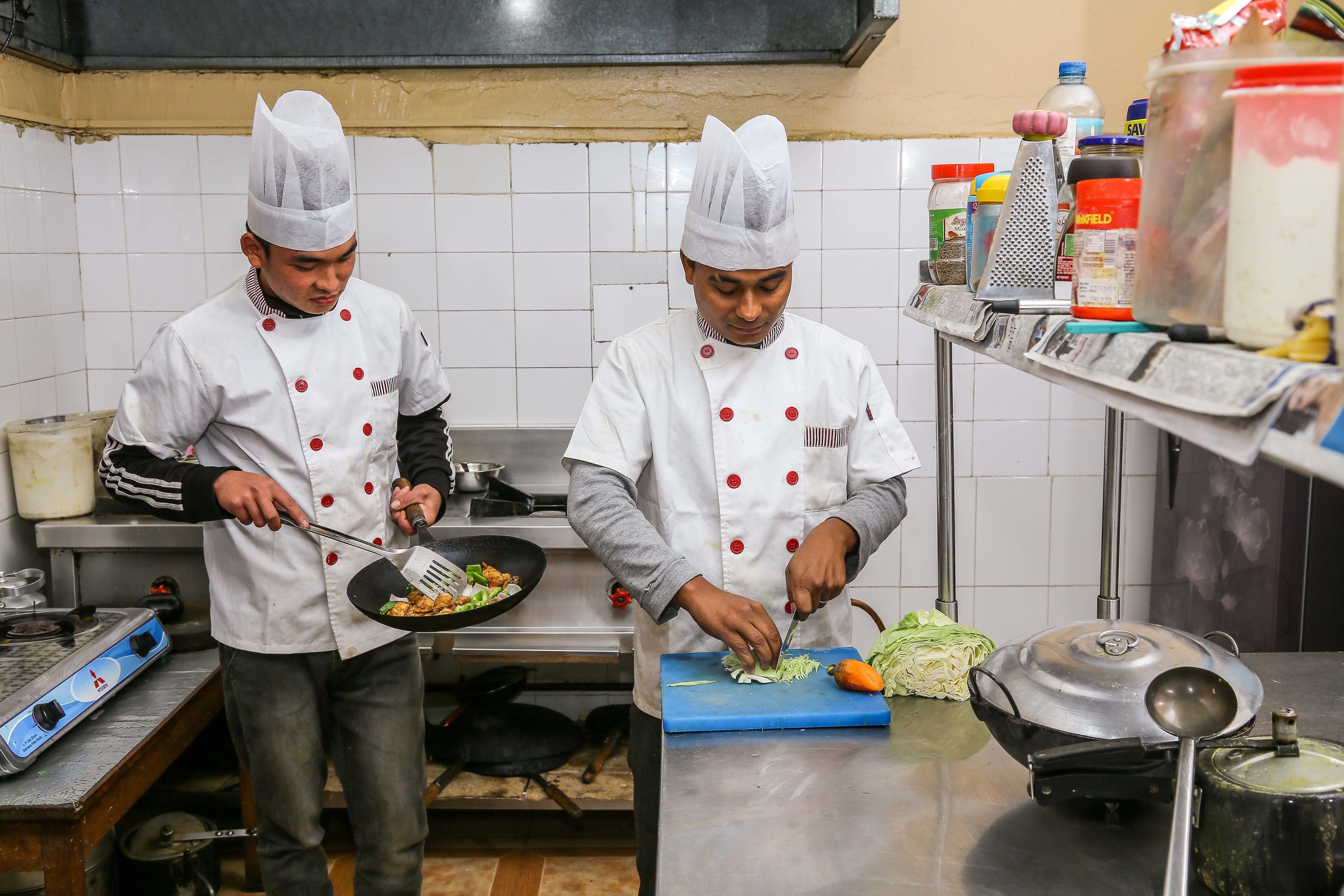 Two chefs in a kitchen preparing food.