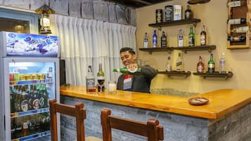 A bar area with a refrigerator stocked with beverages, shelves with liquor bottles, and a bar counter.