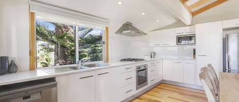 A modern kitchen with white cabinetry, a stainless steel dishwasher, a gas stove, and a microwave.