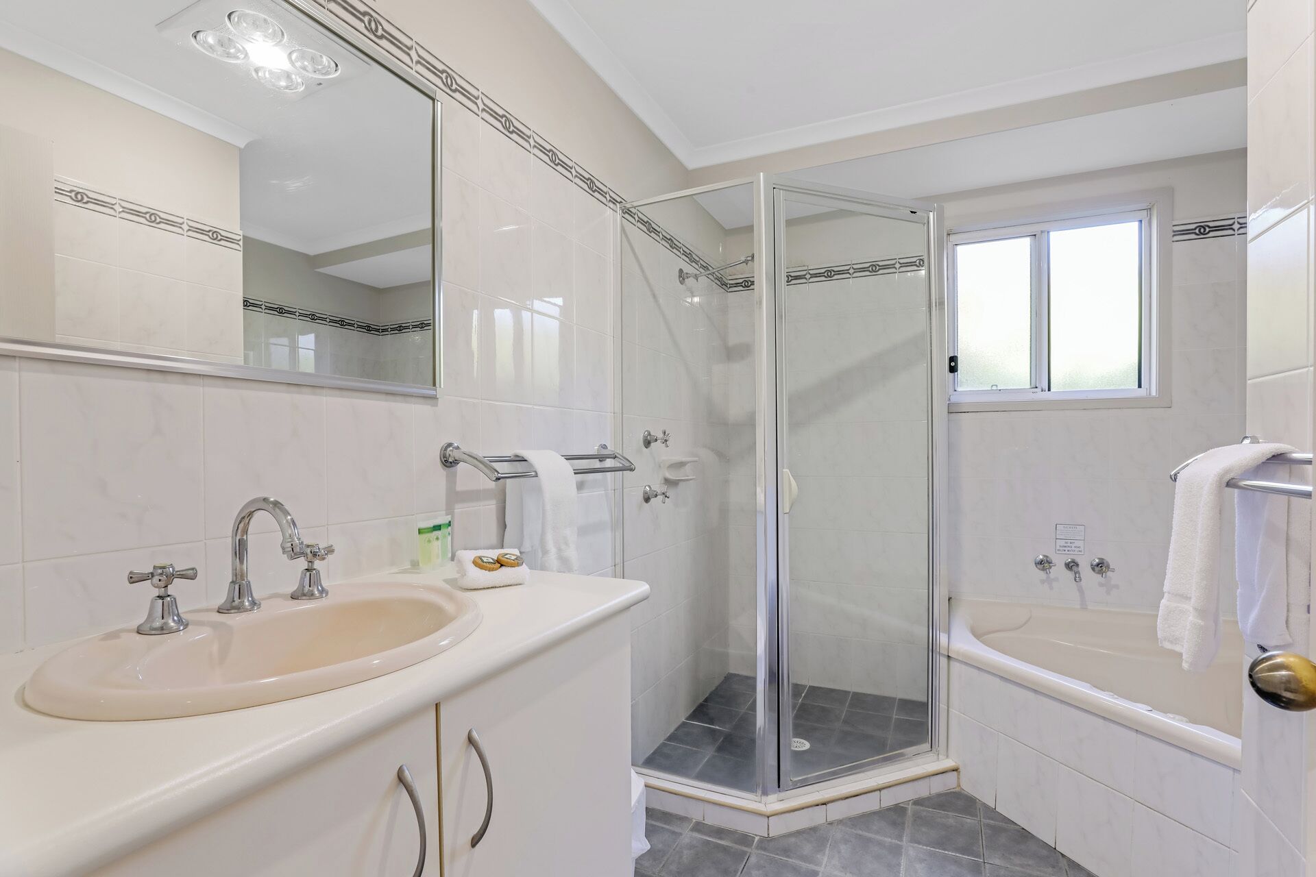 Un baño moderno con ducha de vidrio, lavamanos con tocador y bañera.