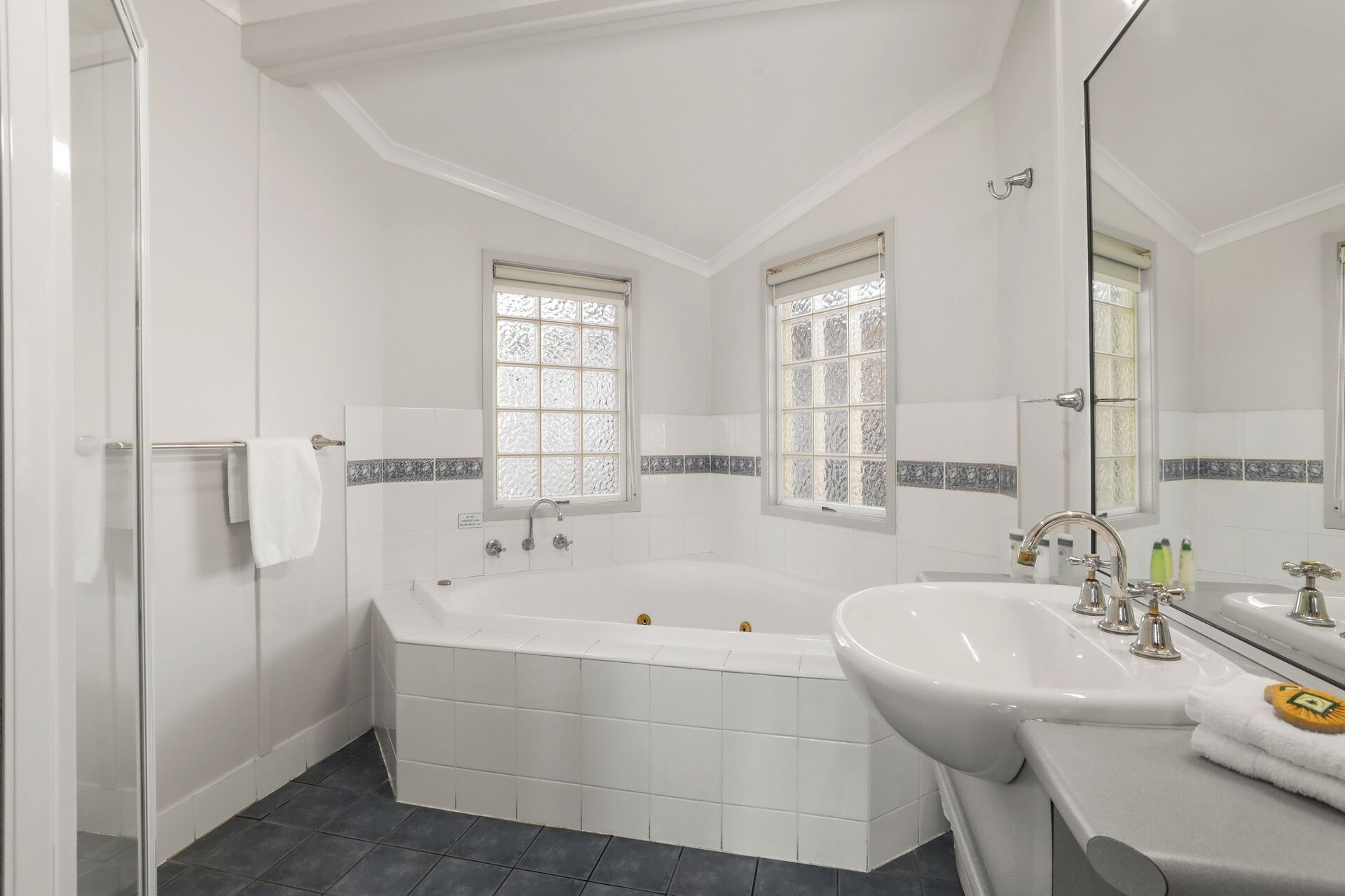 A bathroom with a large bathtub, two sinks, and a mirror.