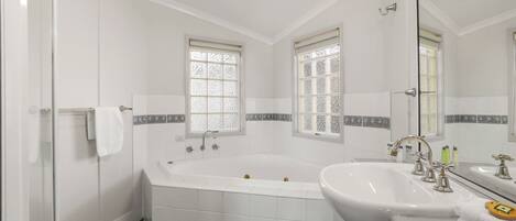 A bathroom with a large bathtub, two sinks, and a mirror.