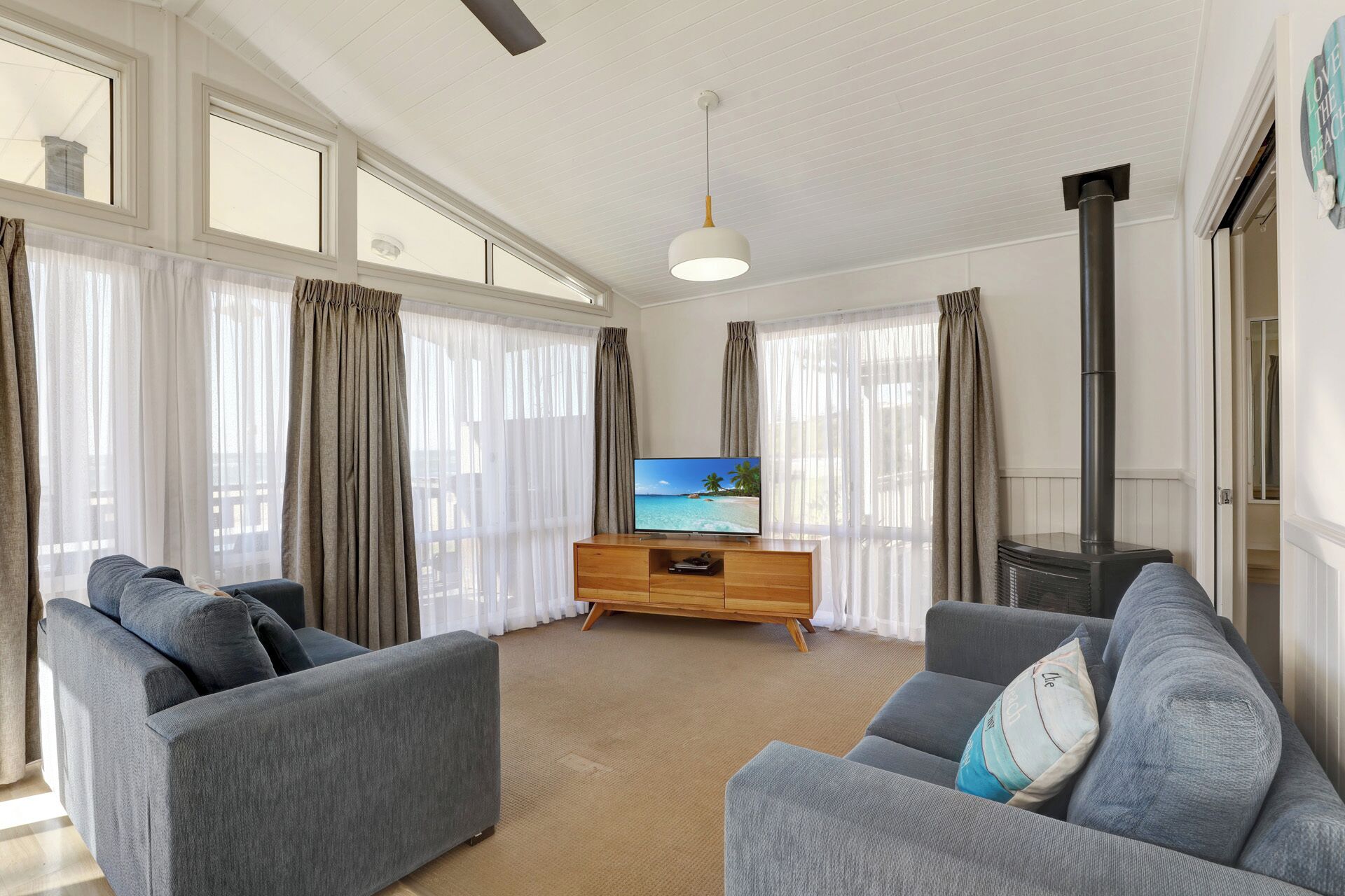A living room with a sofa set, a TV on a wooden stand, and a fireplace.