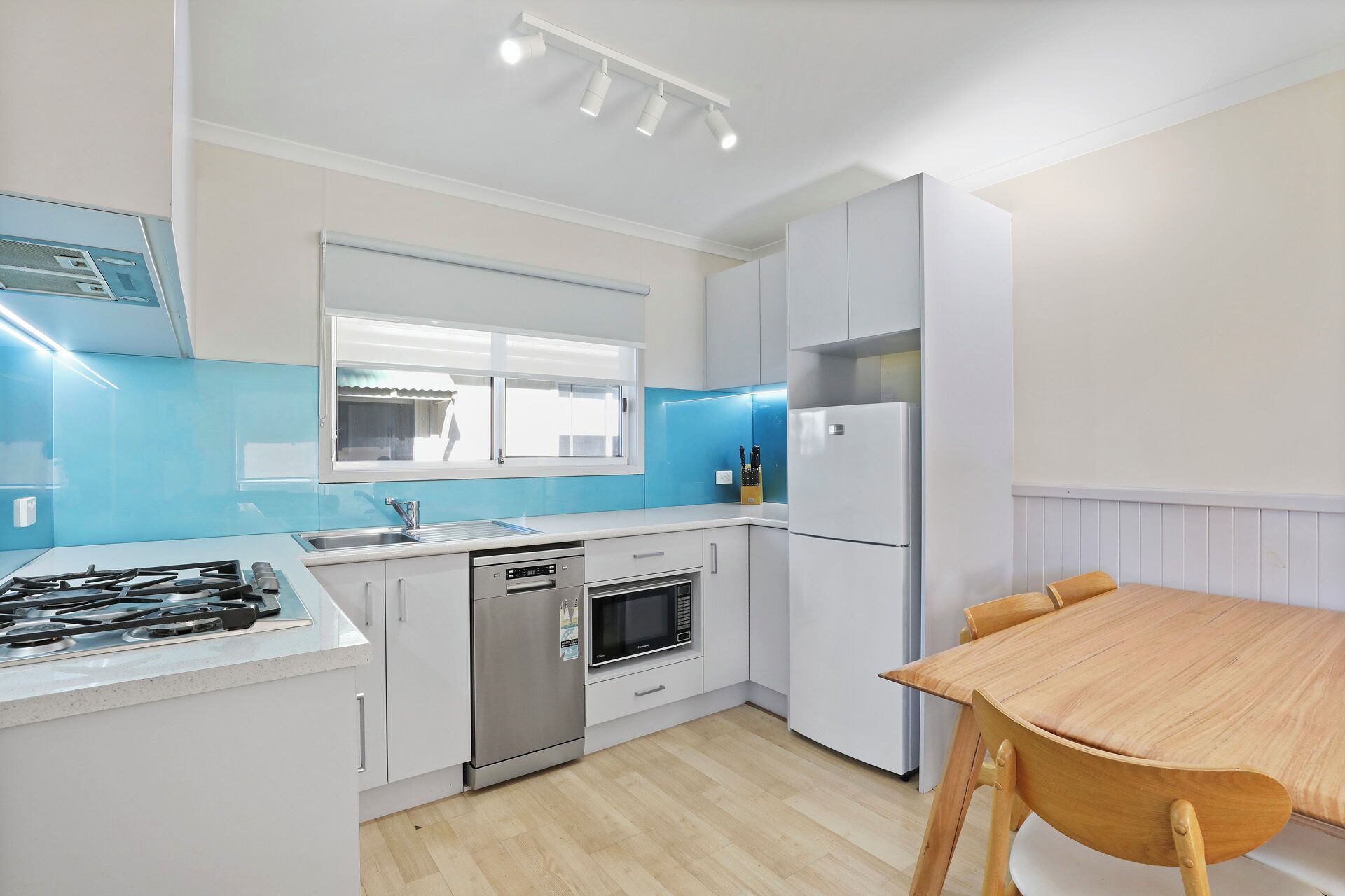 A compact kitchen with white cabinets, a stainless steel stove, a dishwasher, and a refrigerator.