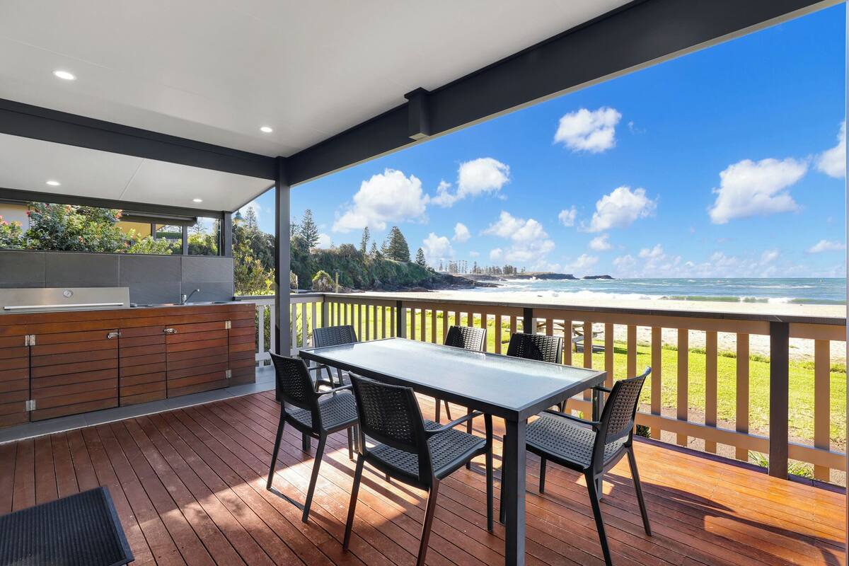 A covered outdoor dining area with a view of the ocean.