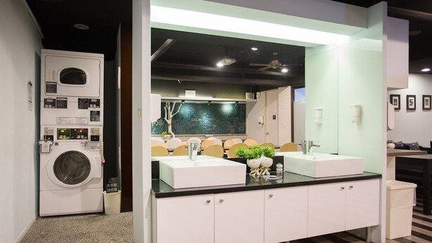 A modern bathroom with a dual sink vanity, a large mirror, and a built-in washing machine. - Fun Inn Taipei Hostel (Taipei)