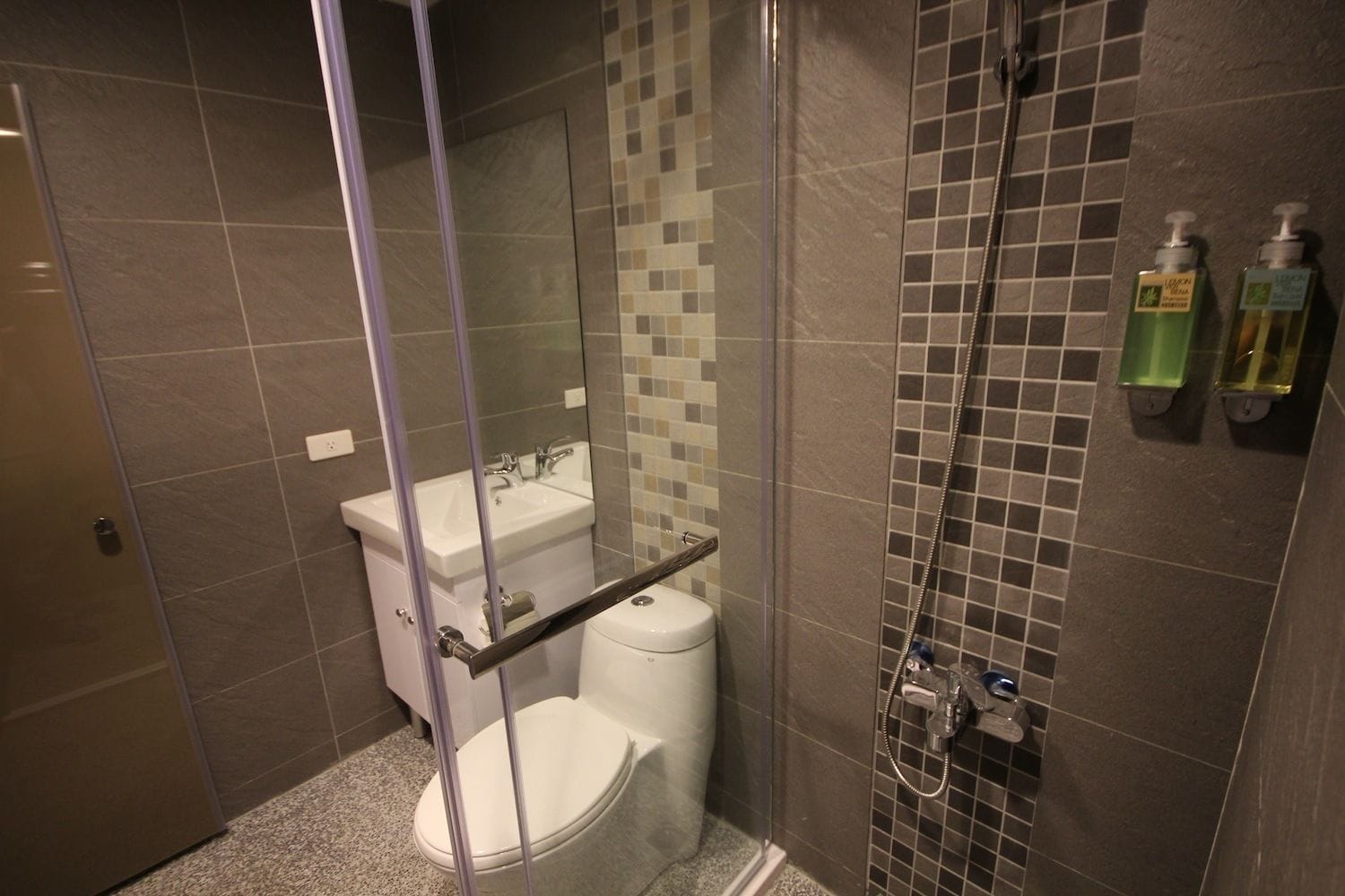 A bathroom with a glass-enclosed shower, a white toilet, and a sink.
