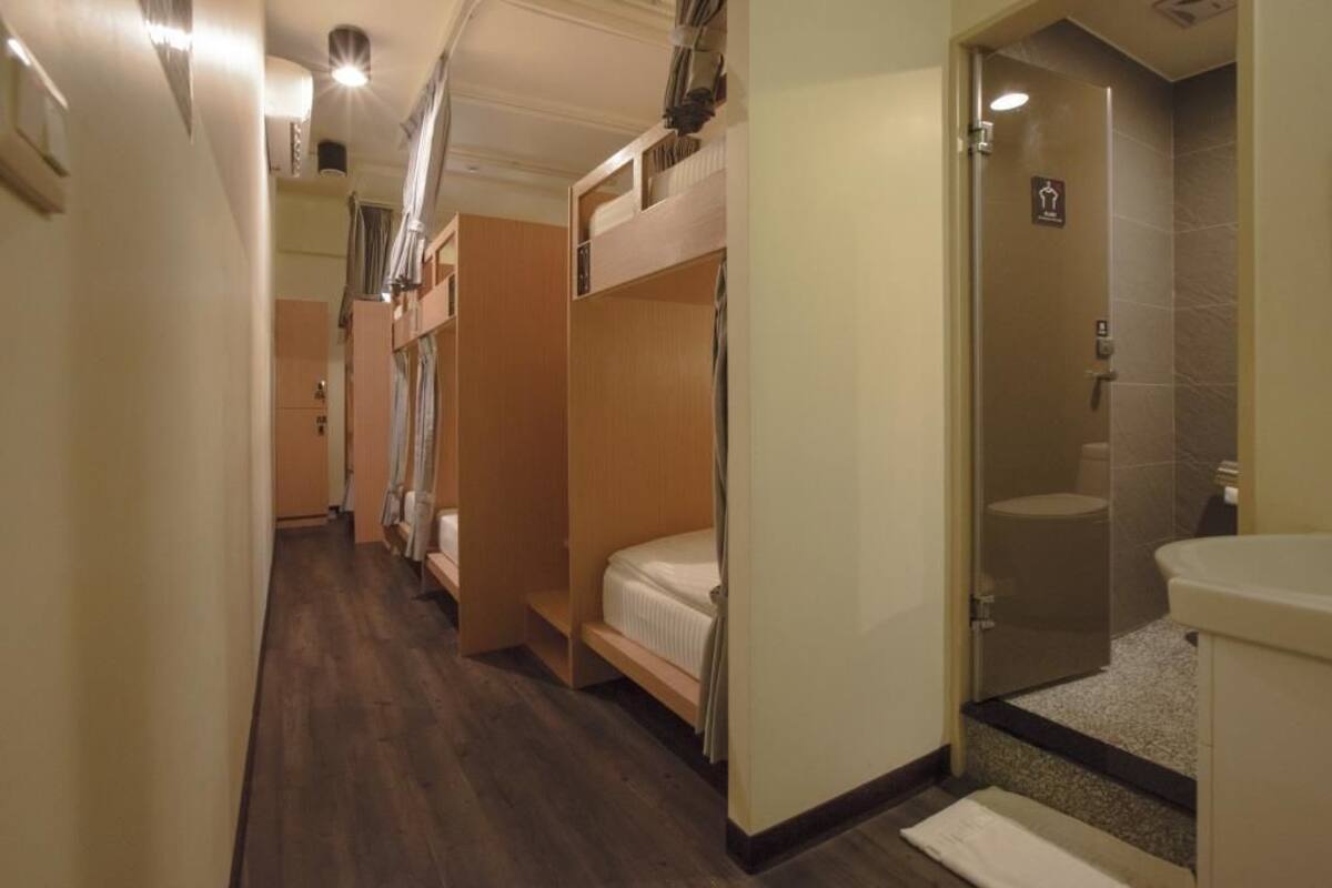 A hotel room with bunk beds, a shower area, and a small kitchenette.