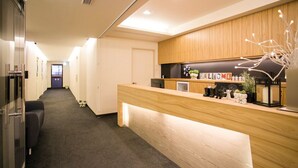 A hotel reception area with a wooden counter, a reception desk, and a hallway leading to rooms. - Fun Inn Taipei Hostel (Taipei)