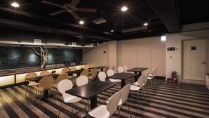 A conference room with tables and chairs, a brick wall, and a ceiling fan. - Fun Inn Taipei Hostel (Taipei)