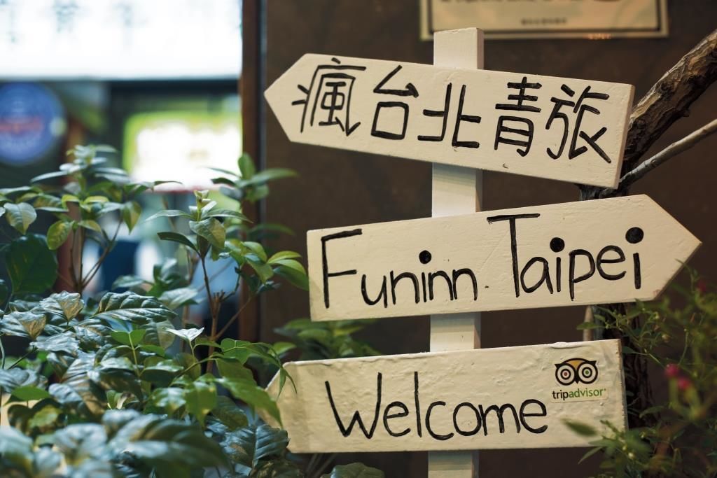 A wooden signpost with directional signs and a welcome message.