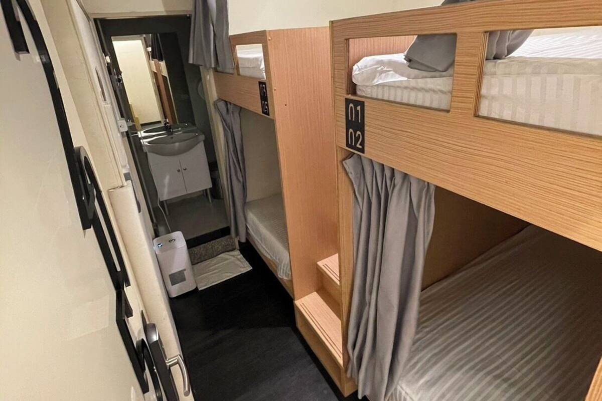 A compact room with bunk beds, a small sink, and a mirror.
