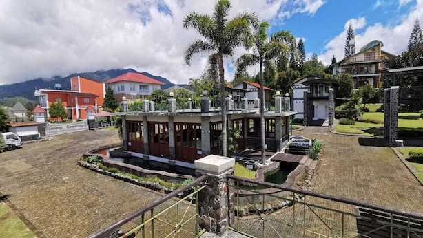 A modern building with a stone facade, a covered patio, and a view of a mountainous landscape.