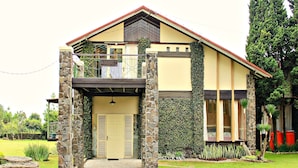 A two-story house with a stone facade, a balcony, and a well-maintained garden.