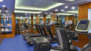 Un gimnasio con cintas de correr, máquinas de pesas y un espejo grande.