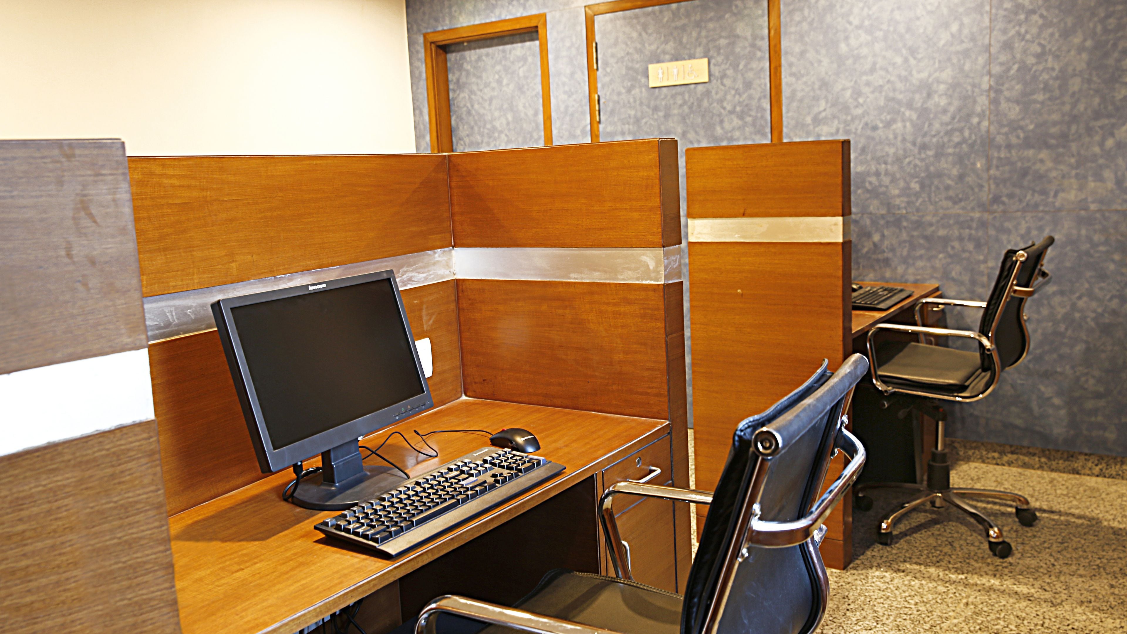 Un petit bureau fermé avec un ordinateur, un clavier et une chaise.