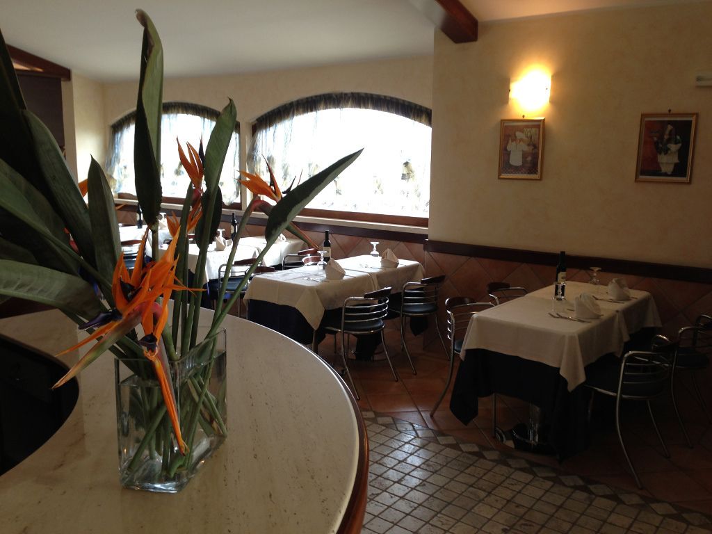 A restaurant interior with tables, chairs, and a vase with flowers.