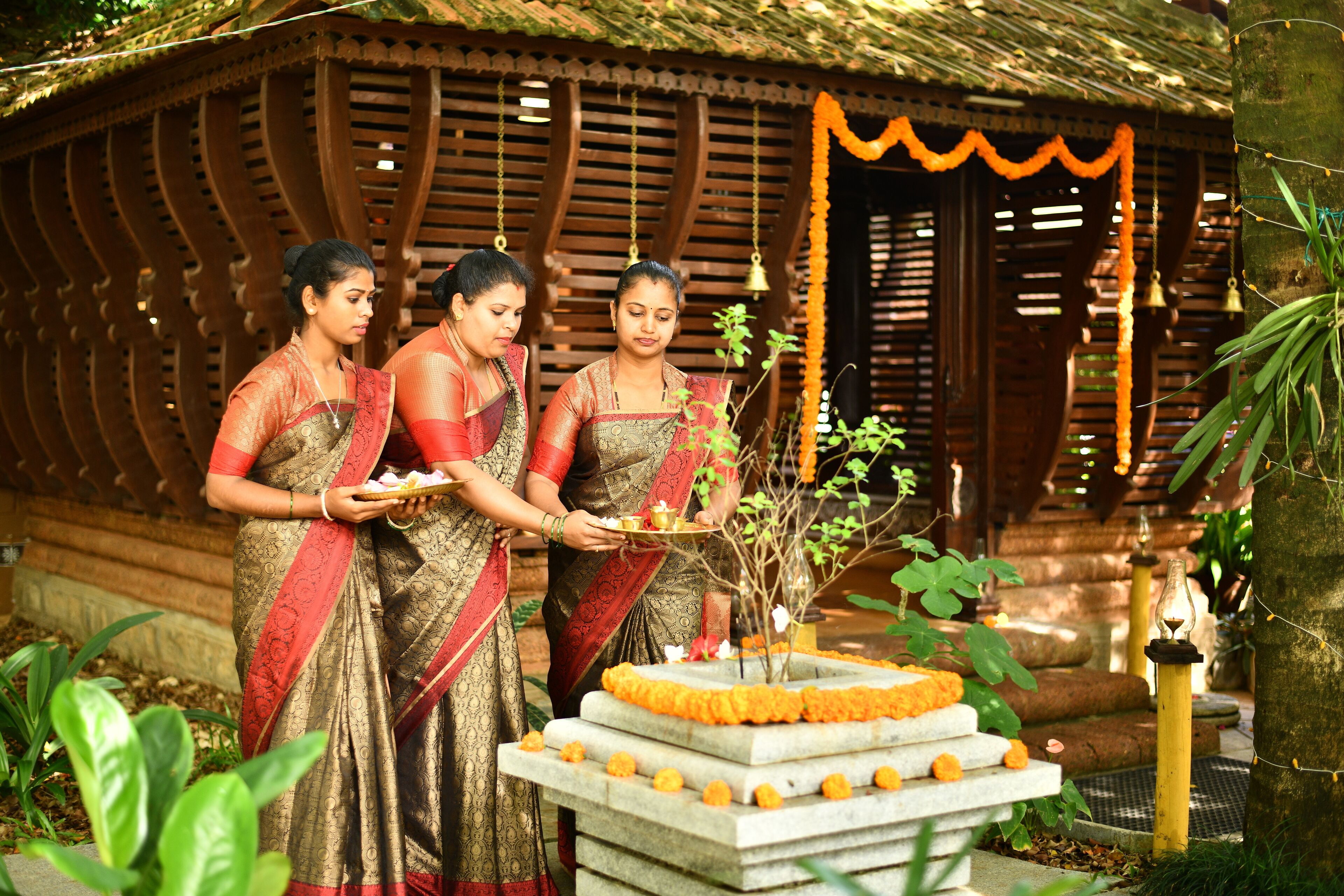A traditional setting with a wooden structure, a small altar with offerings, and a decorative plant.