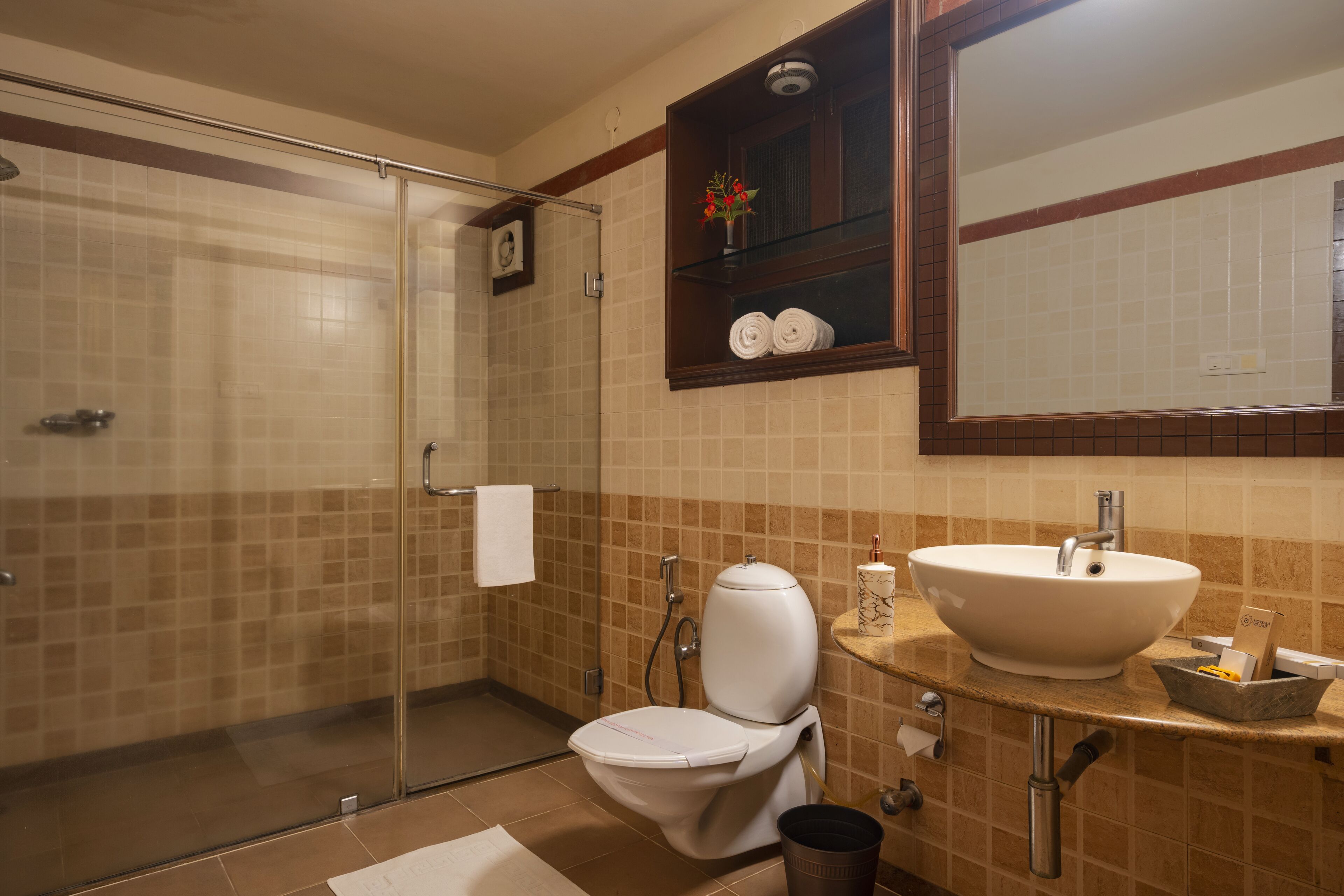 A bathroom with a glass shower enclosure, a white toilet, a sink with a marble countertop, and a mirror above the sink.