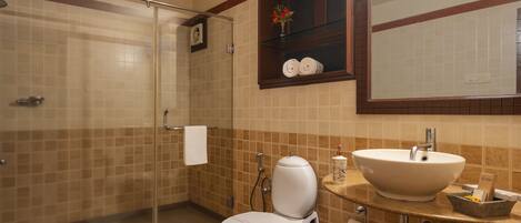 A bathroom with a glass shower enclosure, a white toilet, a sink with a marble countertop, and a mirror above the sink.