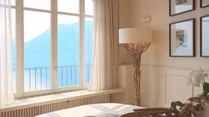 Una habitación con un ventanal grande que da a una montaña, una mesa redonda con mantel blanco y una lámpara de pie de diseño peculiar.