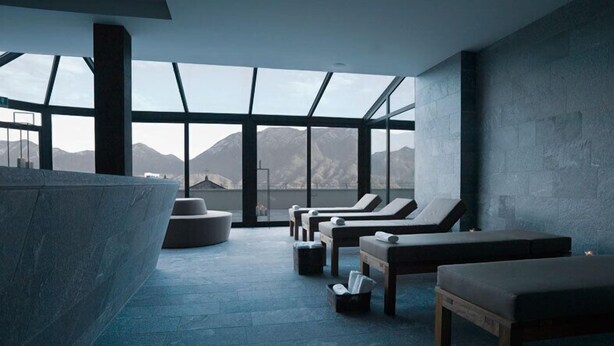 Un moderno spa con un tragaluz grande, suelo de piedra y vistas a las montañas.