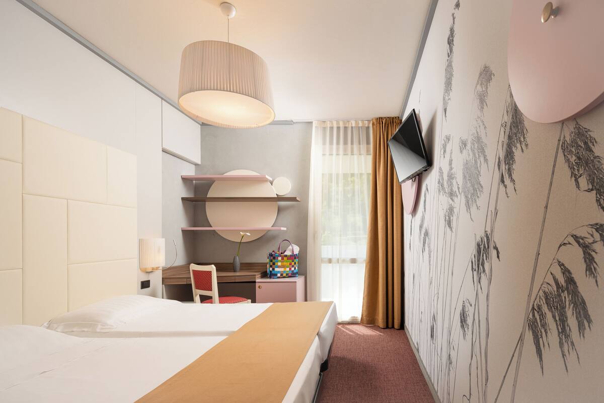 Une chambre d’hôtel équipée d’un lit, d’un bureau, d’une chaise et d’une télévision.