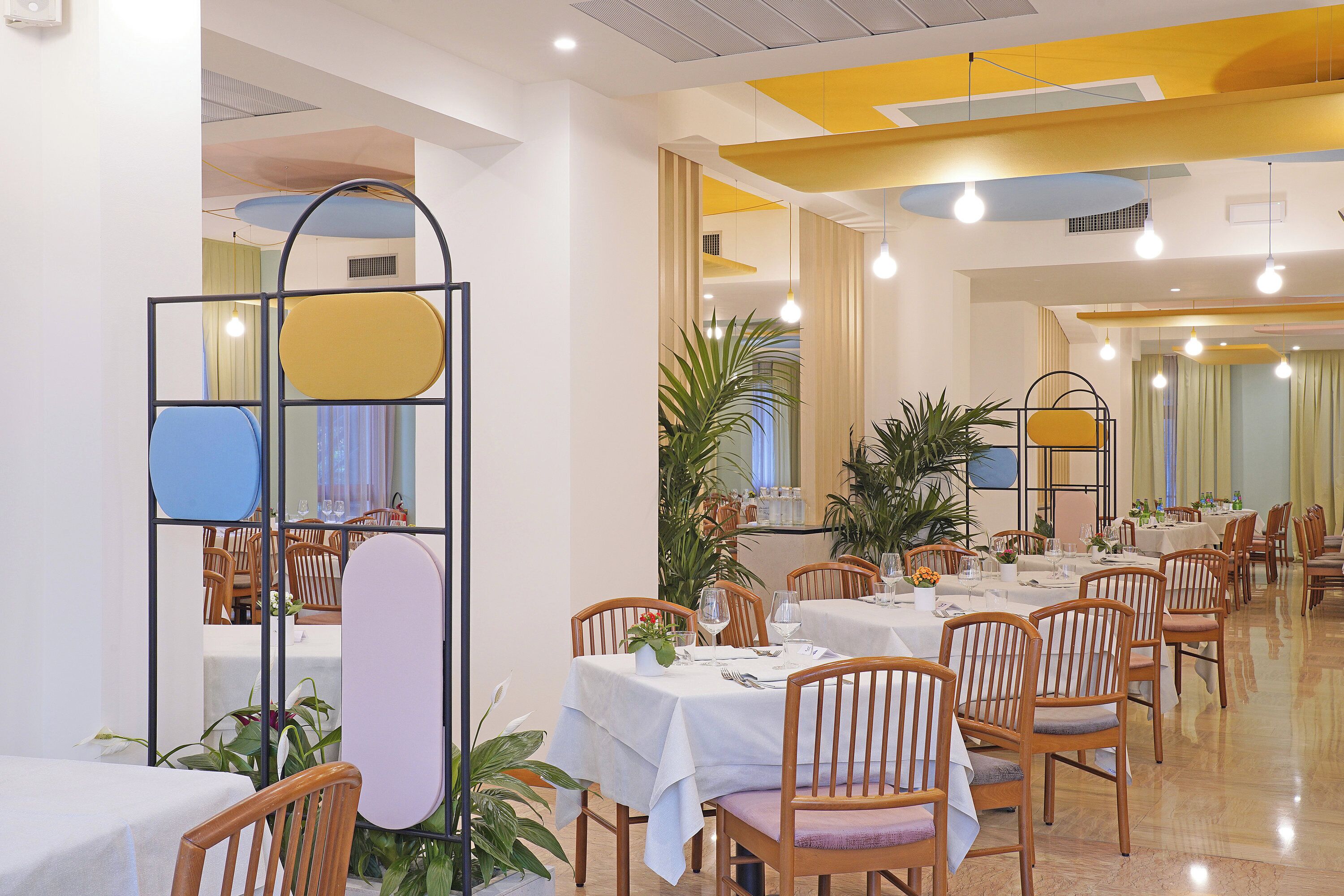 Un comedor con varias mesas y sillas, algunas con plantas.