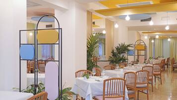 Un comedor con varias mesas y sillas, algunas con plantas.