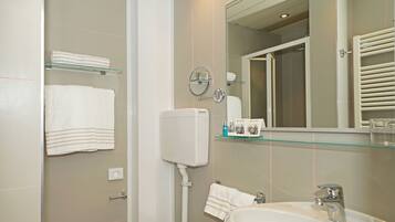 Een moderne badkamer met toilet, wastafel en glazen planken.
