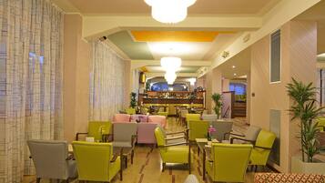 Vestíbulo de hotel con zona de bar, diversas opciones de asientos, incluyendo sillas y sofás, y un techo decorativo.