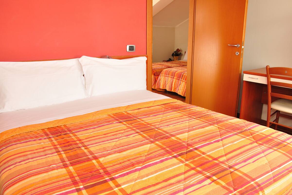 A hotel room with a bed, a desk, and a chair.