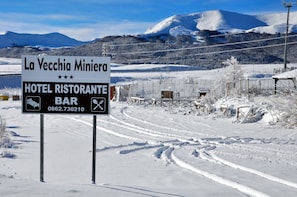 A sign for La Vecchia Miniera Hotel Ristorante Bar with a snowy mountain backdrop. - Hotel La Vecchia Miniera (Lucoli)