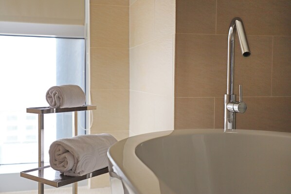 Un baño moderno con una bañera independiente, un perchero con toallas y una ventana que proporciona luz natural.