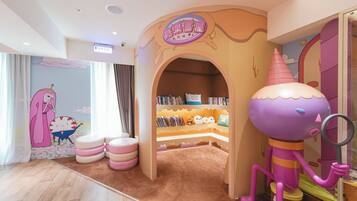 A children's play area with a cartoon character, a bookshelf, and a pink character statue.