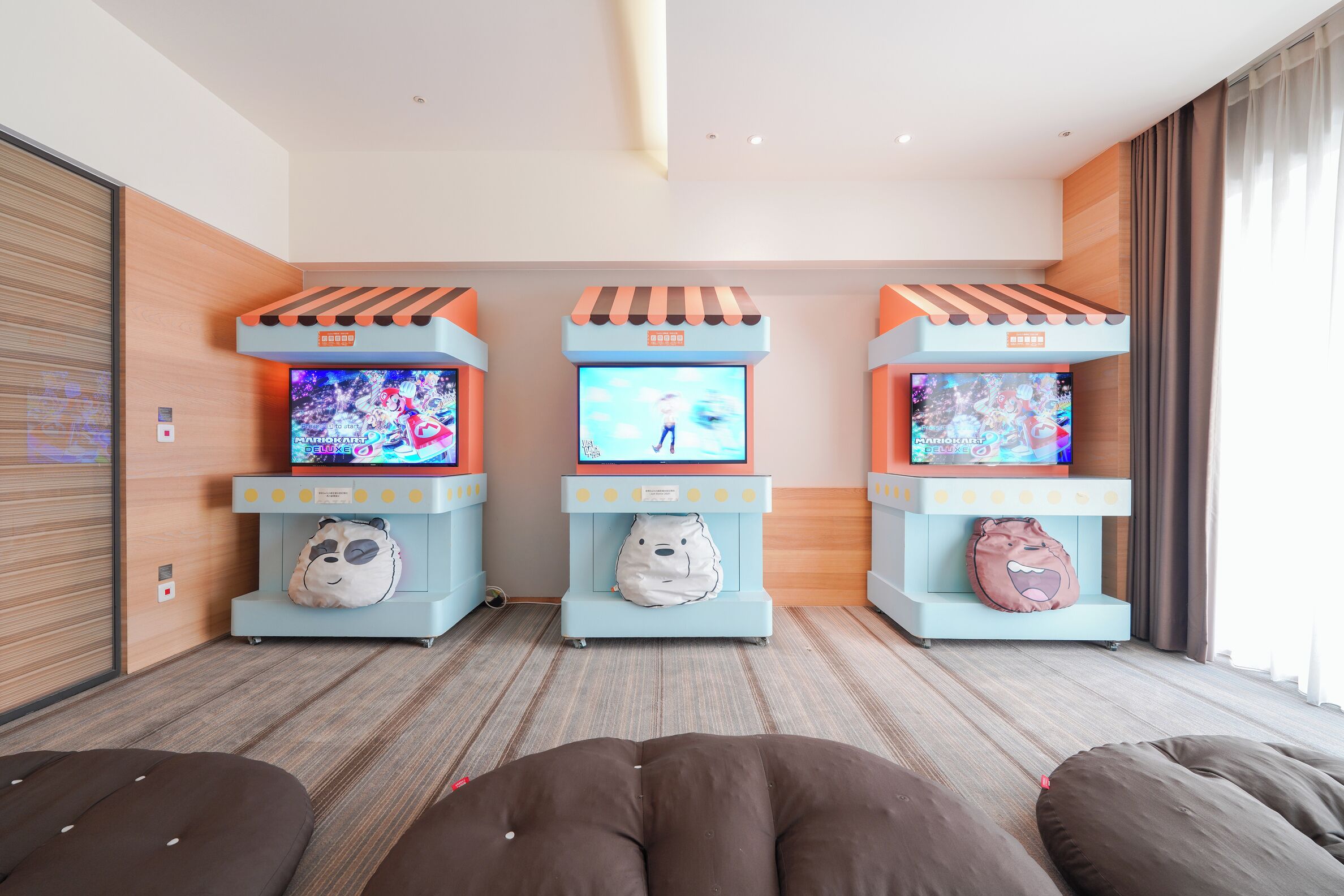 A room with three gaming stations, each with a TV and a plush toy.
