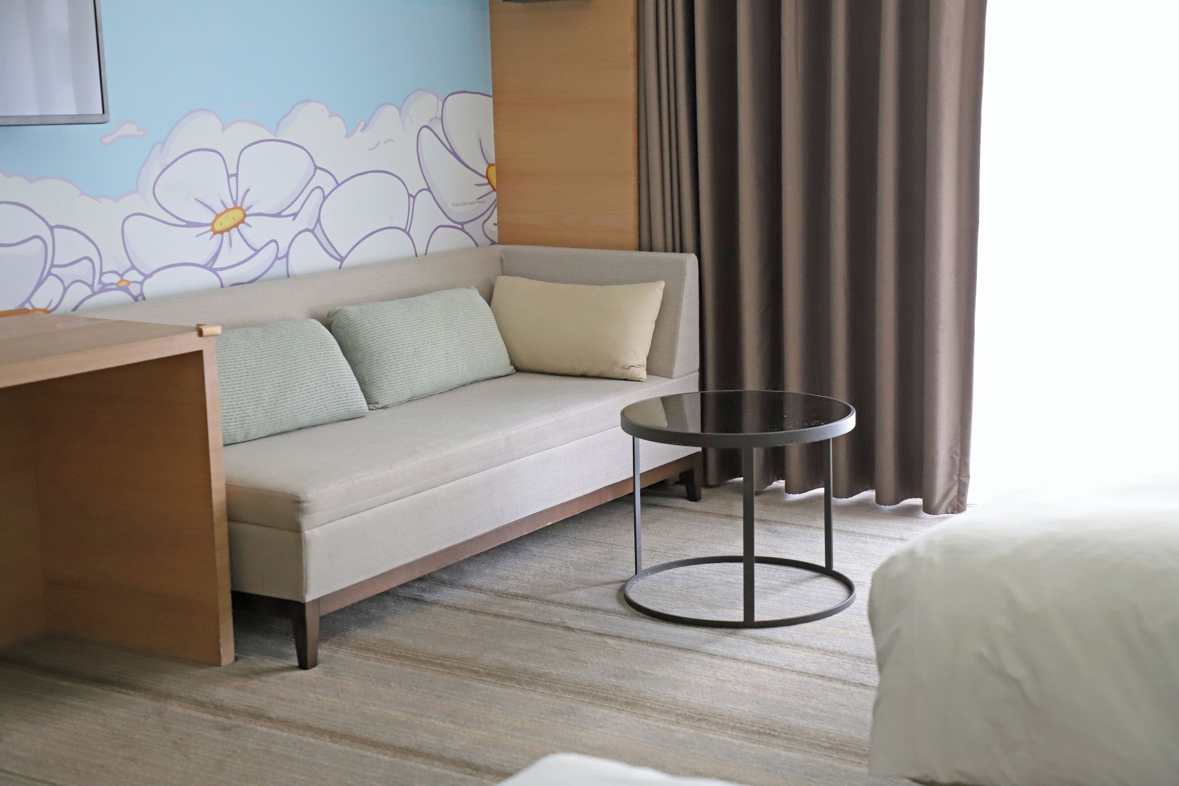 A hotel room with a sofa, a small round table, and a bed.