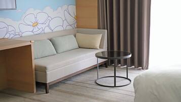 A hotel room with a sofa, a small round table, and a bed.