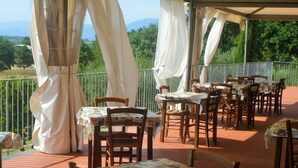 An outdoor patio with tables and chairs, covered by white canopies, overlooking a green landscape with trees and mountains. - Corte Tommasi Residence (Castelfranco di Sotto)