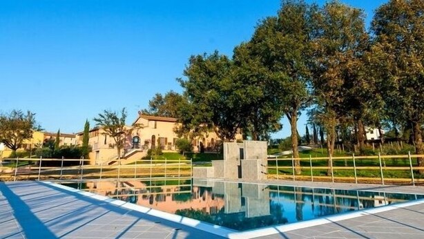 A swimming pool with a clear reflection, surrounded by a fence and trees. - Corte Tommasi Residence (Castelfranco di Sotto)